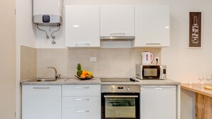 Una cucina moderna con mobili bianchi, elettrodomestici in acciaio inossidabile, forno e microonde.