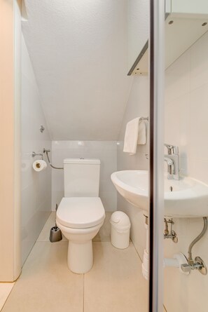 Une petite salle de bain moderne, équipée de toilettes, d’un lavabo et d’une serviette accrochée au mur.