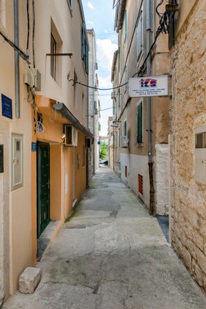 Une rue étroite, bordée de bâtiments des deux côtés, une enseigne avec du texte en cyrillique et une porte avec un numéro.