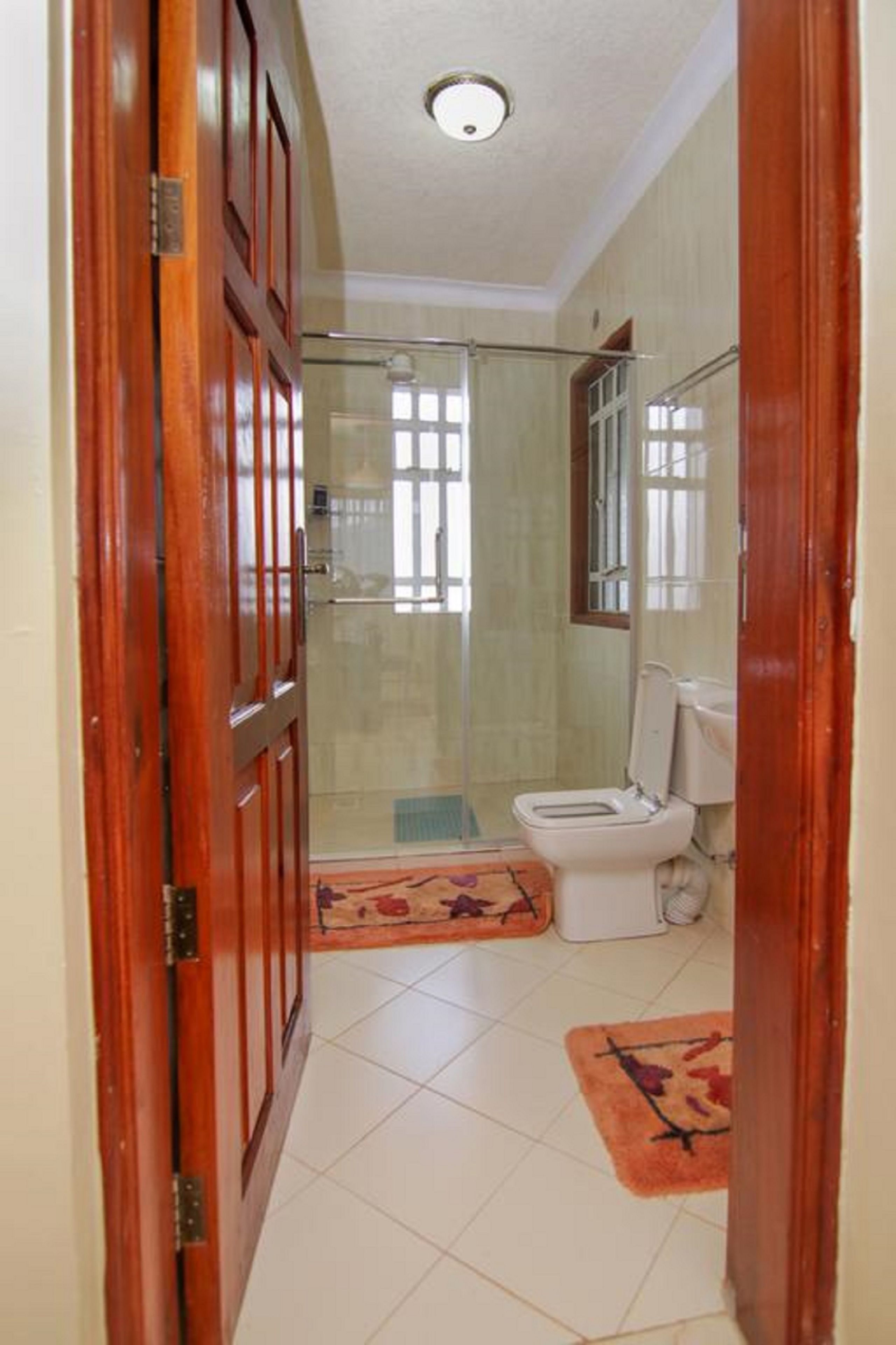A bathroom with a toilet, a shower, and a wooden door.