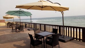 A seaside patio with outdoor seating and umbrellas, overlooking the ocean. - Hotel Riviera Ramatou Plage (Lomé)