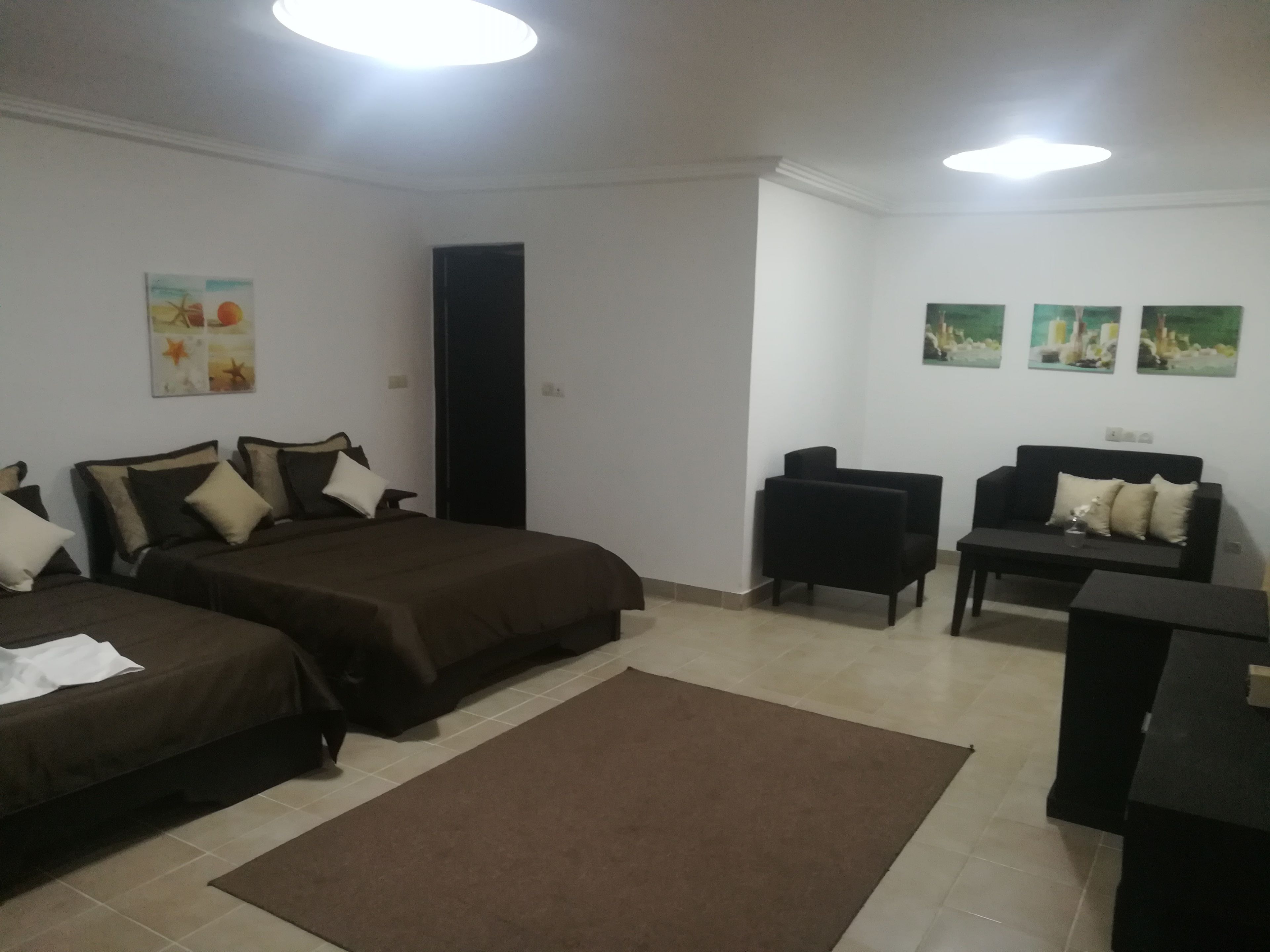 Una habitación de hotel con dos camas, un sofá, una mesita y una alfombra.