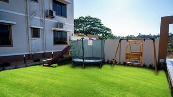A rooftop with a trampoline, a slide, and a netted play area.