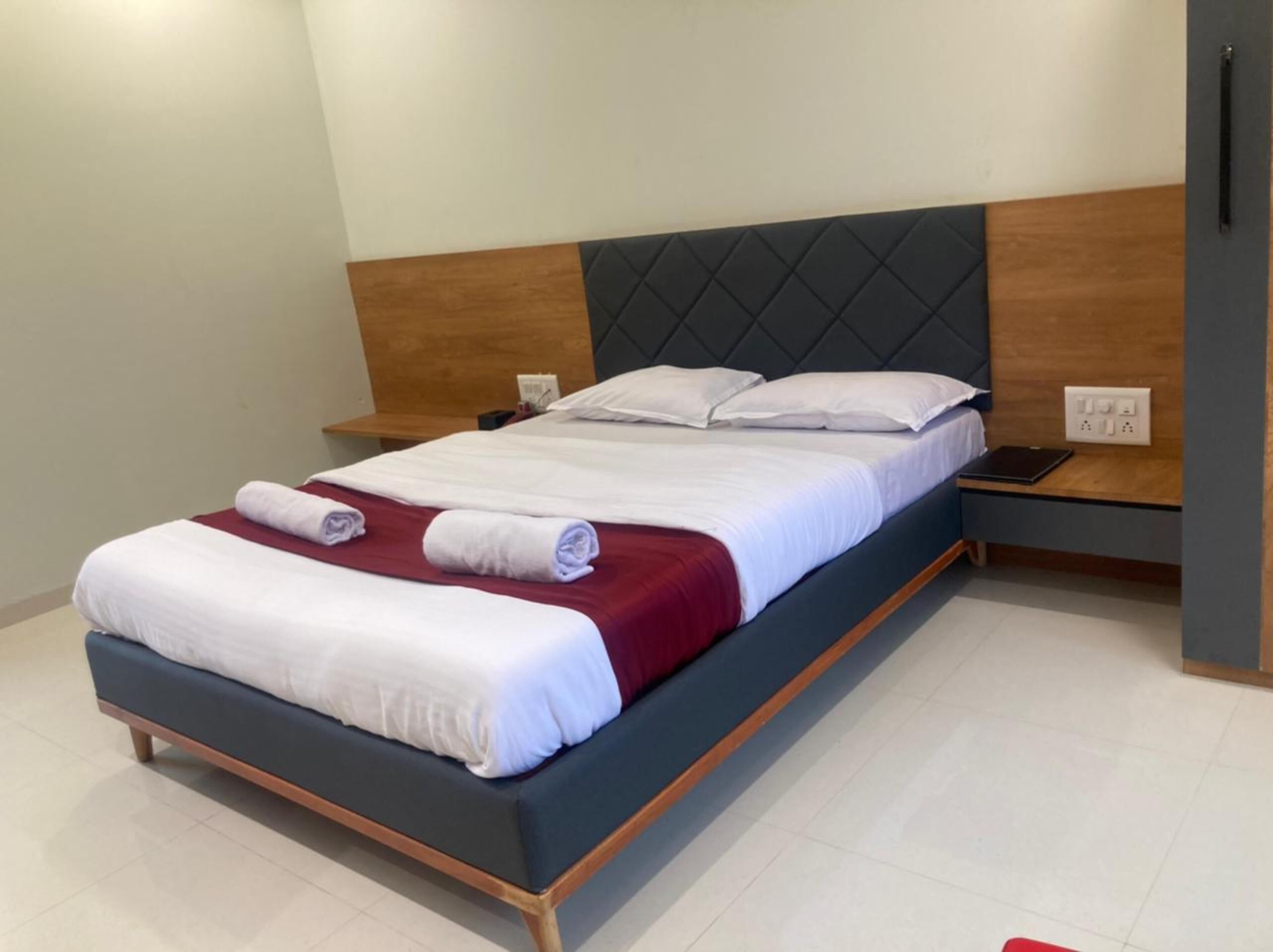 A modern hotel room with a bed, bedside tables, and a nightstand.