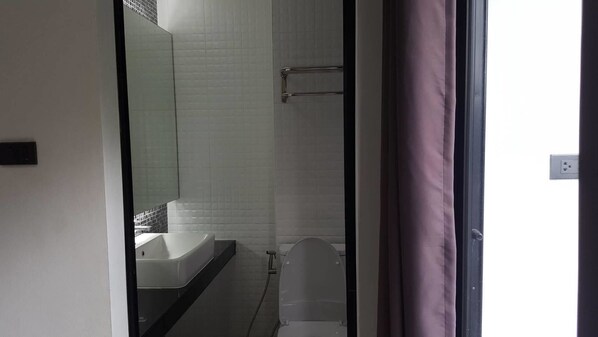 Un baño con lavamanos blanco, inodoro y zona de ducha.
