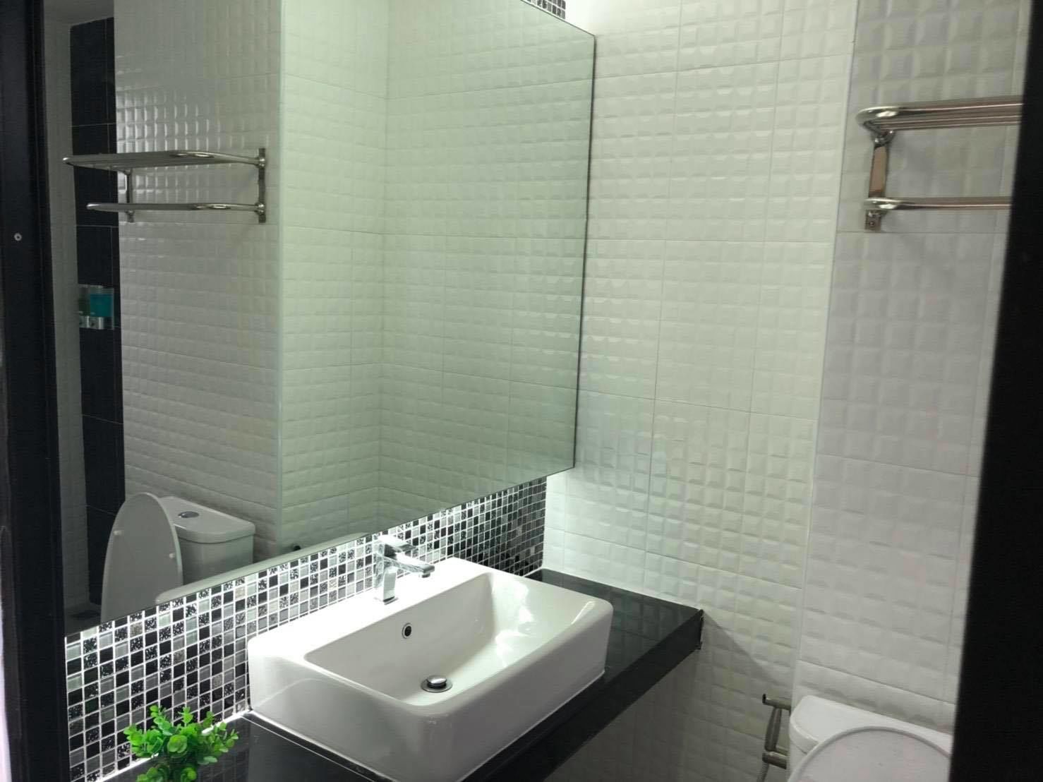 A modern bathroom with a white sink, black countertop, and a large mirror.