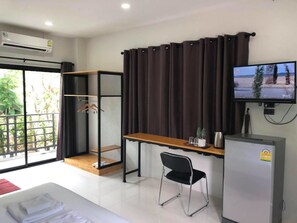 Habitación de hotel moderna con cama, escritorio, silla, televisor y mini refrigerador.