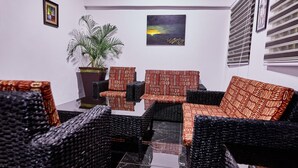 A seating area with patterned sofas and chairs, a potted plant, and artwork on the wall. - Janjay Hotel (Accra)