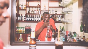A bar area with shelves stocked with various bottles and glasses. - Janjay Hotel (Accra)