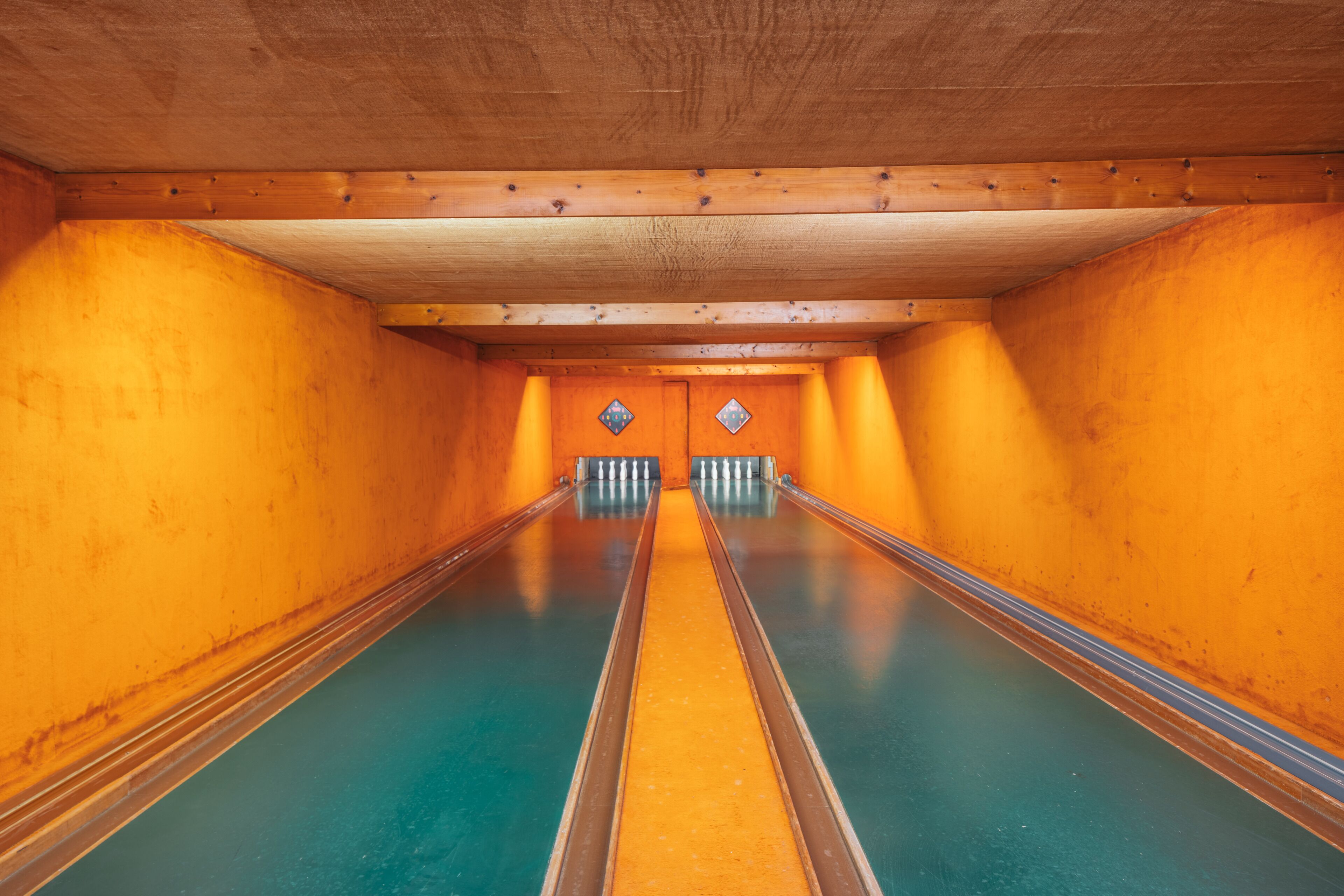 Une salle de bowling avec des murs en bois et une piste centrale.