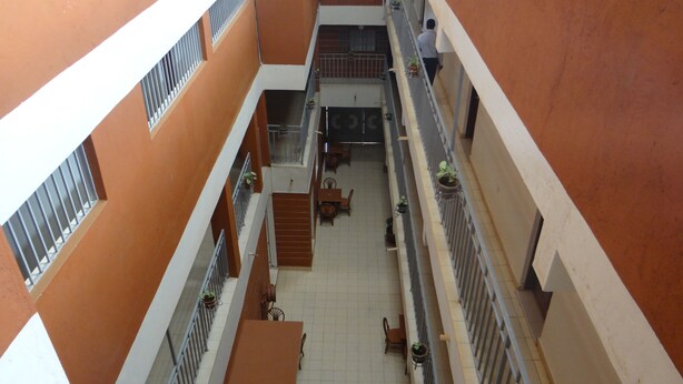 A multi-level atrium with a central staircase, potted plants, and a seating area. - Bykay Hotel (Sega)
