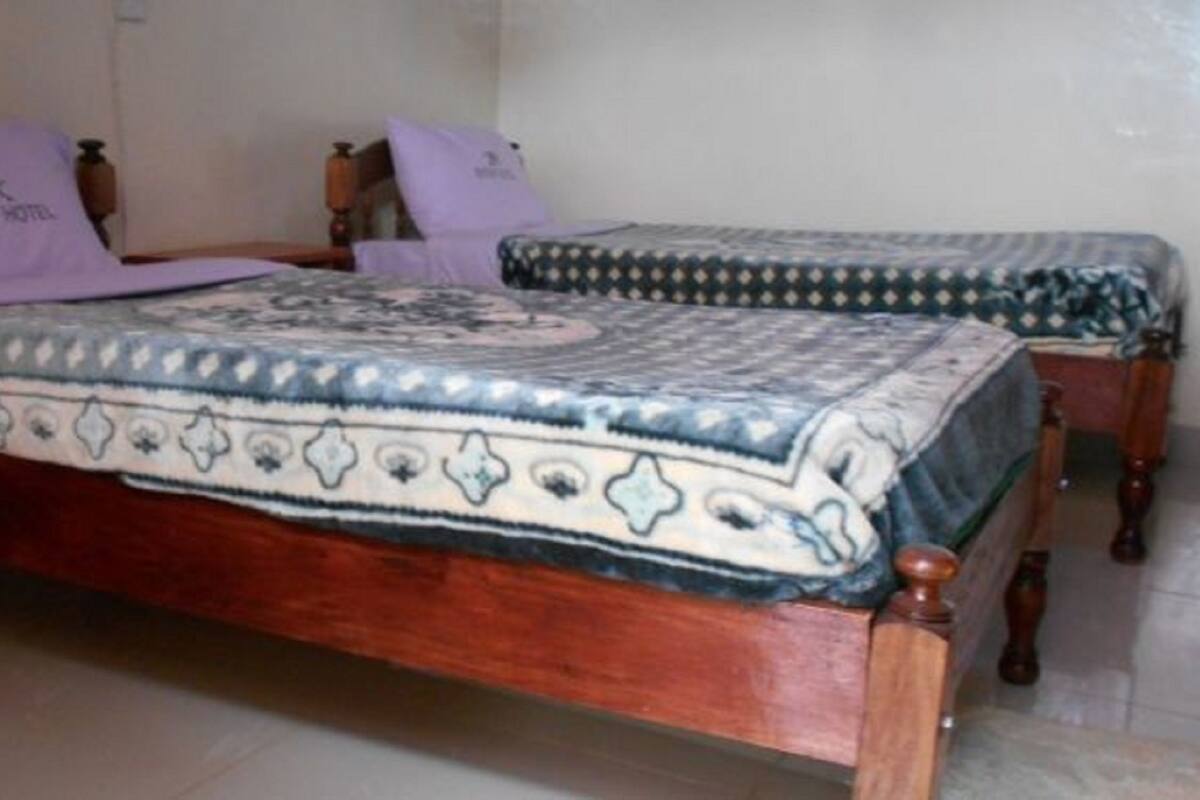 A room with two wooden beds, each with a patterned bedspread and pillows.