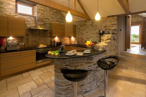 Una cocina moderna con una isla de piedra, taburetes de bar y vistas al exterior.