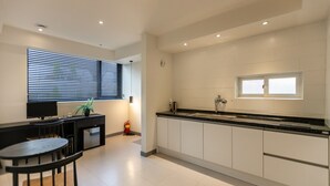 A modern kitchen with white cabinets, a black countertop, and a window with blinds. - Busan Haeundae Hotel A (Busan)