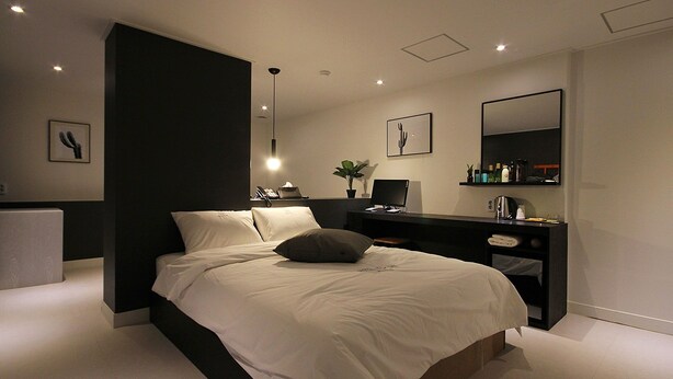 A modern bedroom with a large bed, bedside tables, a desk, and a mirror. - Busan Haeundae Hotel A (Busan)