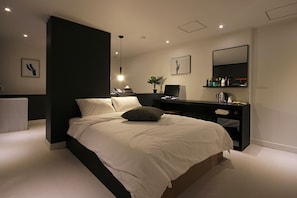 A modern bedroom with a large bed, bedside tables, a desk, and a mirror. - Busan Haeundae Hotel A (Busan)