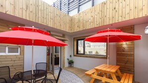A wooden interior with a round table and chairs, two red umbrellas, and a wooden bench. - Busan Haeundae Hotel A (Busan)
