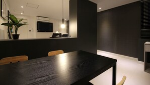 A modern dining area with a black table and wooden chairs, a potted plant, and recessed ceiling lighting. - Busan Haeundae Hotel A (Busan)