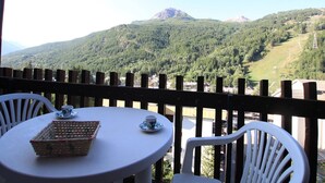 A table with a basket and a cup, set against a backdrop of a mountainous landscape.
