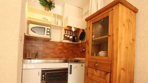 A compact kitchen with a microwave, oven, and wooden cabinet.