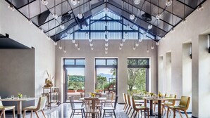 A spacious dining area with high ceilings, large windows, and modern lighting fixtures.