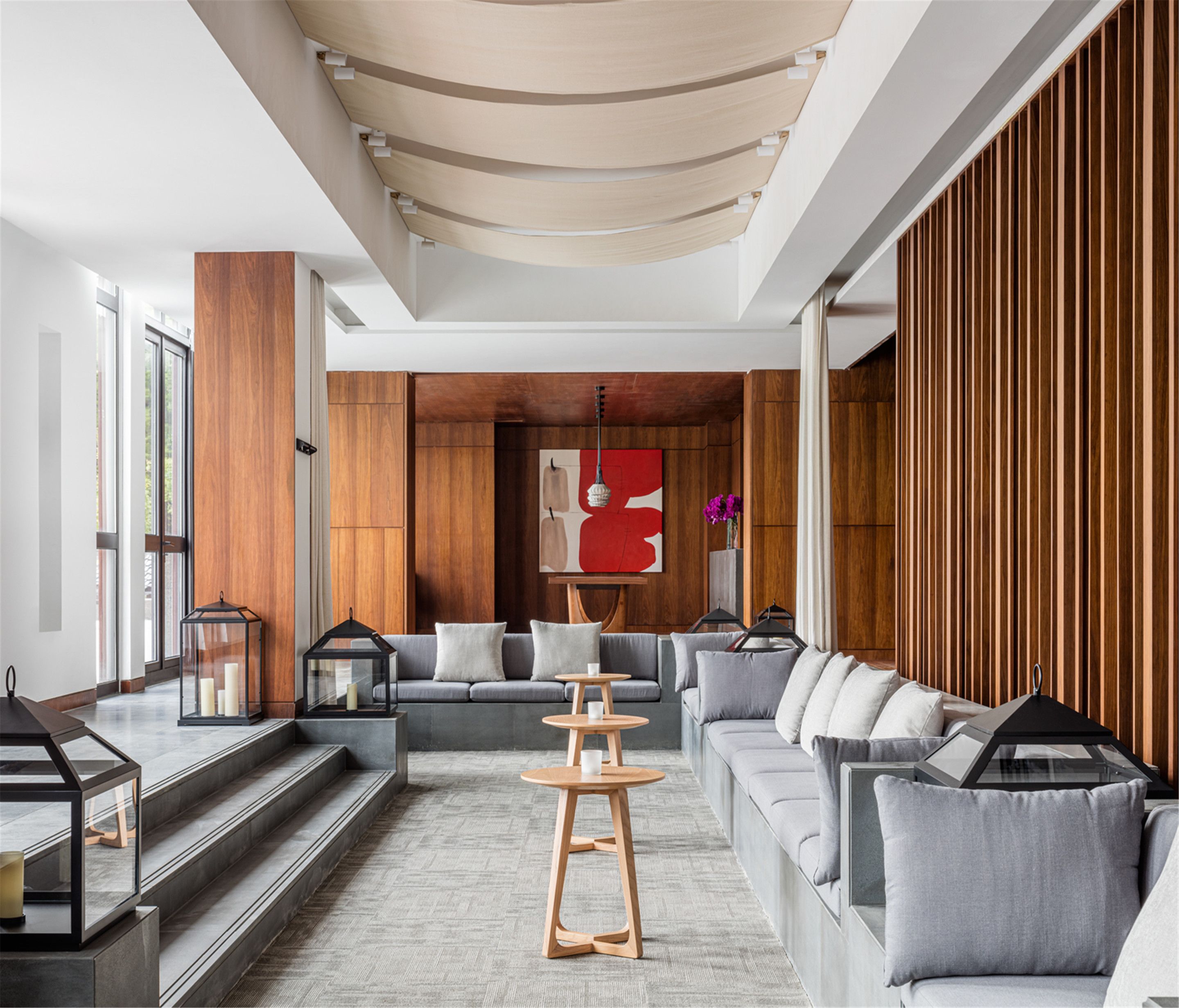 A modern living room with a grey sofa, wooden accents, and a large abstract painting.