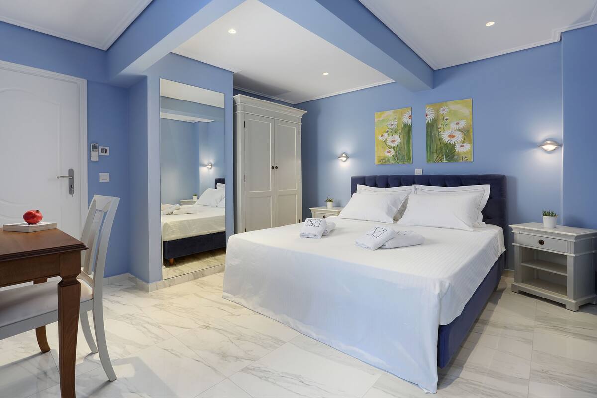 A bedroom with a bed, bedside tables, a nightstand, a chair, a table, and a mirror.