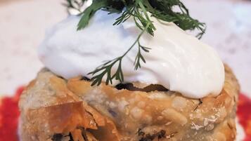 A dish with a creamy topping and a garnish of green herbs.