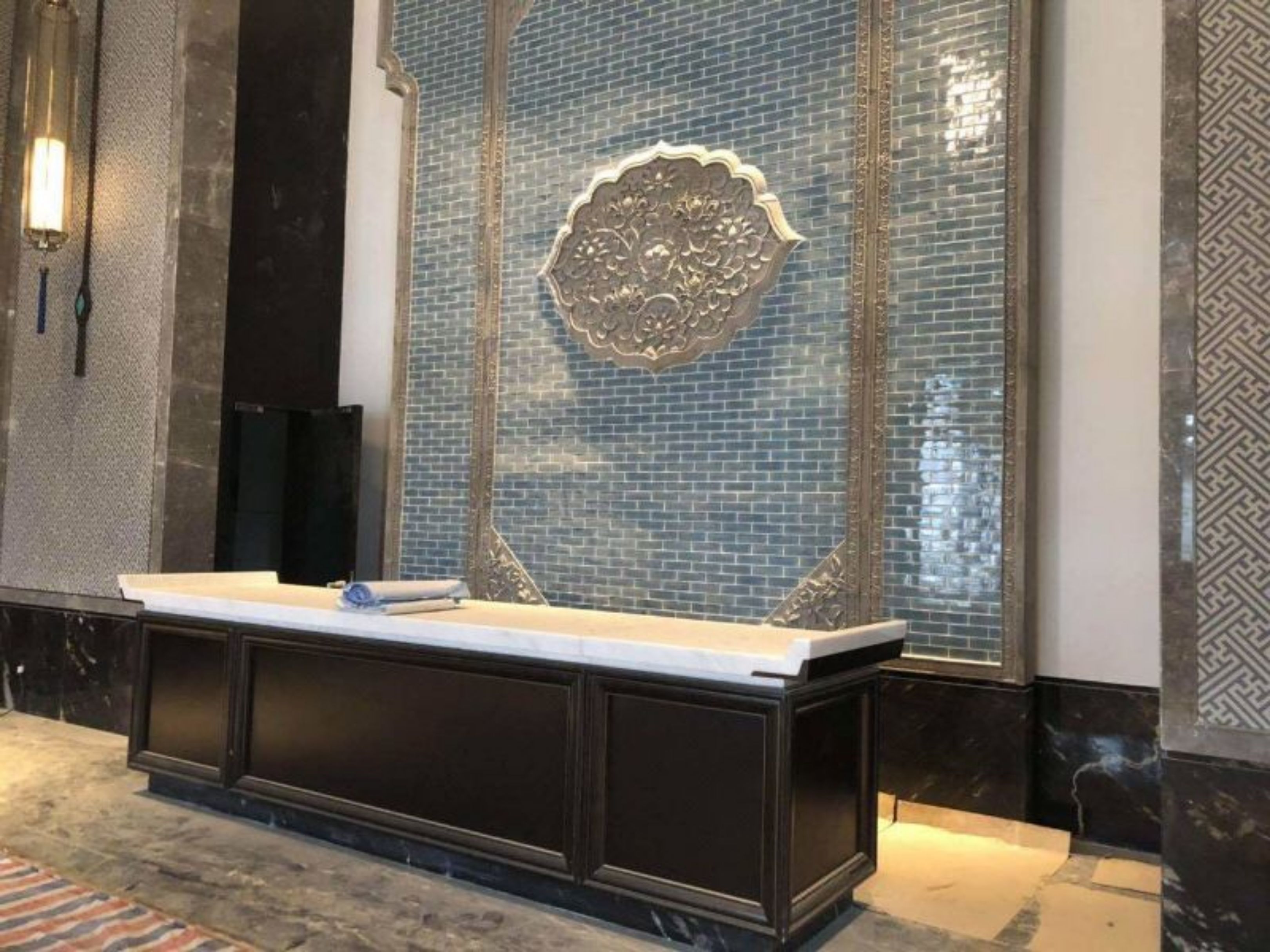 A reception area with a marble counter, a decorative blue-tiled wall, and a patterned floor.