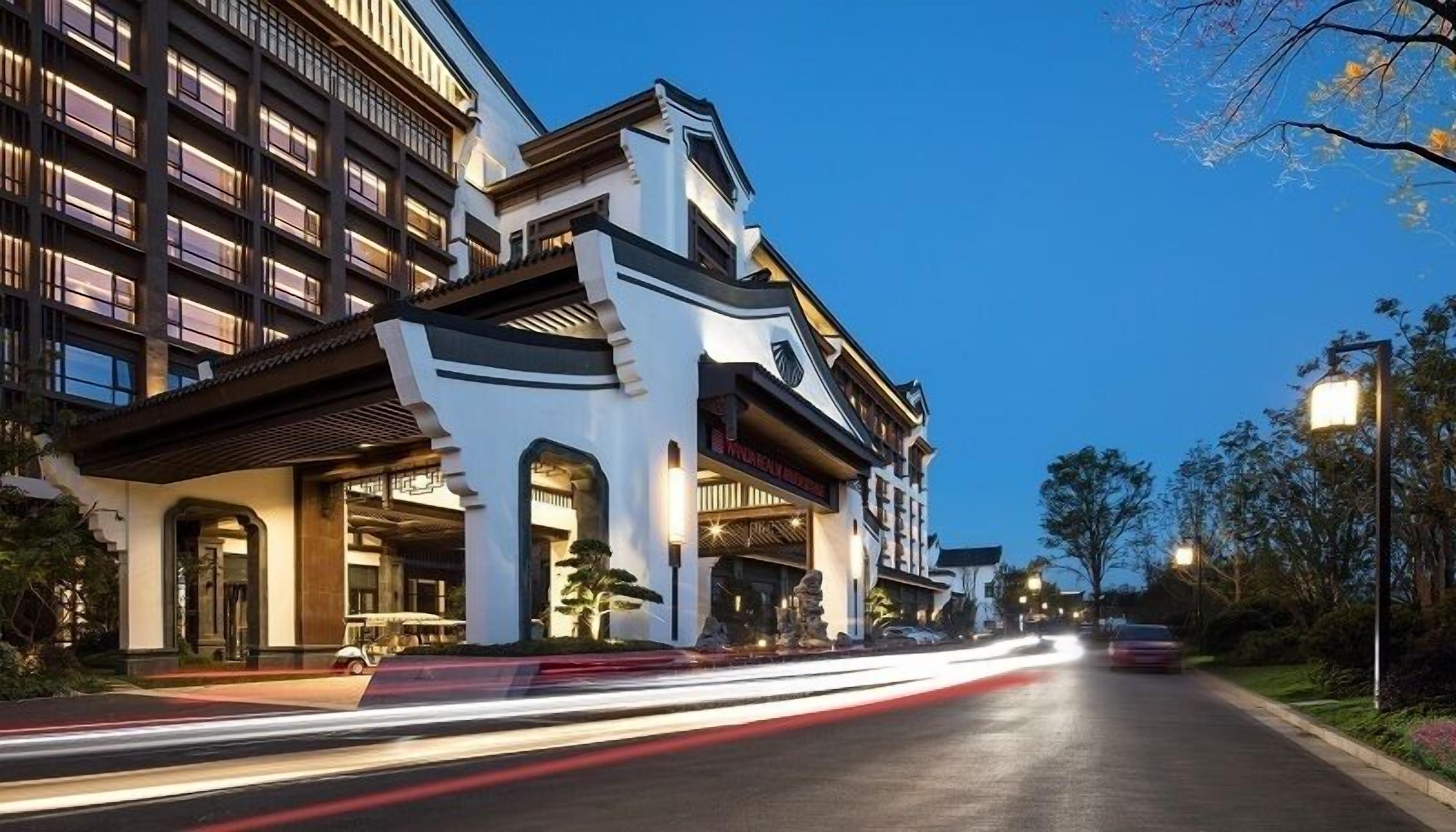 Un hotel de varios pisos con un diseño arquitectónico moderno, que cuenta con una entrada destacada con un corredor cubierto y un cartel sobre la puerta.
