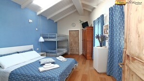 A bedroom with bunk beds, a wooden wardrobe, a desk with a vase, and a blue floral curtain. - Tramontodivino B&B (Ravenna)