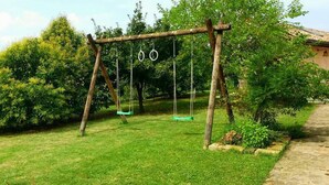 A wooden swing set in a grassy area with trees and a stone pathway. - Tramontodivino B&B (Ravenna)