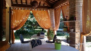 A covered patio with a table and chairs, surrounded by potted plants and a brick wall. - Tramontodivino B&B (Ravenna)