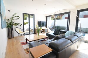 A modern living room with a leather sofa, a coffee table, a chair, and a large window.