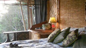 A room with a bed, a wooden table, a lamp, and a view of trees outside. - The Osa Peninsula is teeming with exotic monkeys, birds, and wildlife.  (Puerto Jiménez)