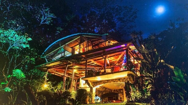 A two-story house with a glass roof and wooden structure, surrounded by lush greenery. - The Osa Peninsula is teeming with exotic monkeys, birds, and wildlife.  (Puerto Jiménez)