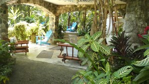 A covered outdoor seating area with stone walls, a wooden bench, and a table with chairs. - The Osa Peninsula is teeming with exotic monkeys, birds, and wildlife.  (Puerto Jiménez)