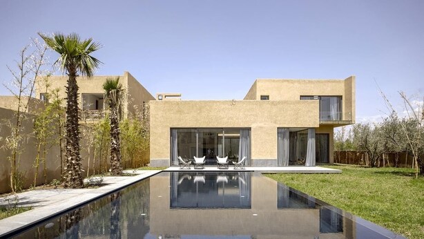 A modern house with a swimming pool, a patio with chairs, and a clear sky. - Villa Amara Oliver Palm Resort (Marrakech)