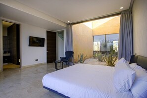 A modern bedroom with a large bed, a TV mounted on the wall, and a view of the outdoors through a sliding glass door. - Villa Amara Oliver Palm Resort (Marrakech)