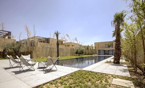 A courtyard with a swimming pool, lounge chairs, and a small garden area. - Villa Amara Oliver Palm Resort (Marrakech)