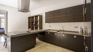 A modern kitchen with dark cabinetry, a central island, and built-in shelves. - Villa Amara Oliver Palm Resort (Marrakech)