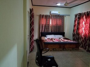 A bedroom with a bed, curtains, an air conditioning unit, and a ceiling fan. - Nass Lodge (Sunyani)