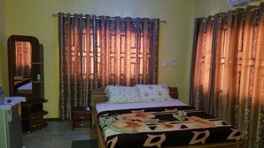 A bedroom with a bed, curtains, a mirror, a desk, and an air conditioner. - Nass Lodge (Sunyani)