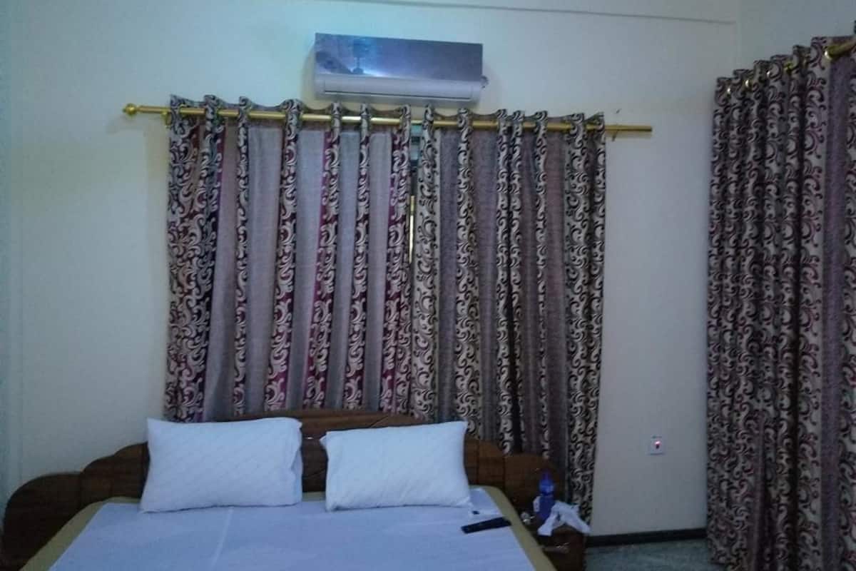 A hotel room with a bed, curtains, and an air conditioning unit.