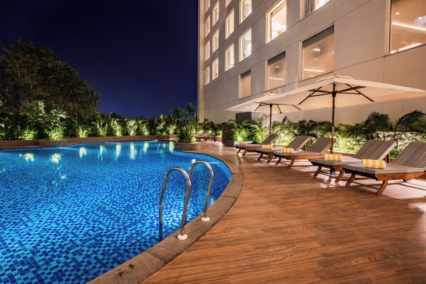 Una piscina al aire libre, sombrillas, sillones reclinables de piscina