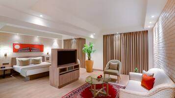 Una sala de estar moderna con un sofá, un televisor, una mesa de centro y una planta grande en maceta.