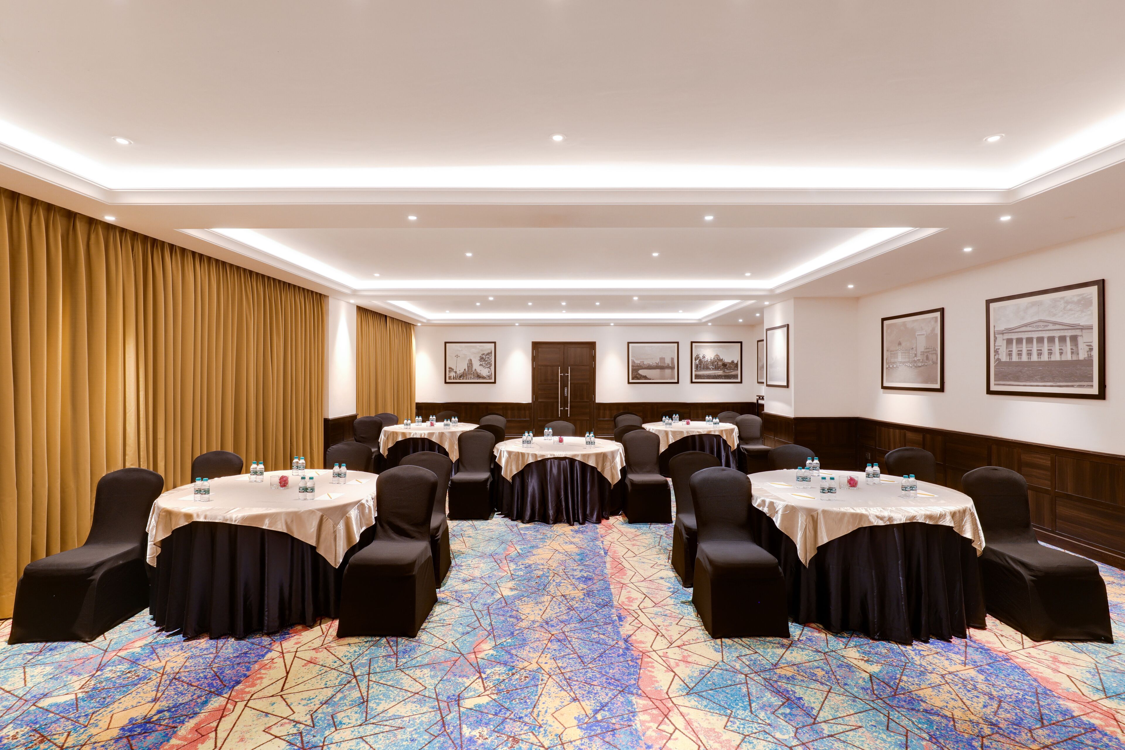 A conference room with round tables, black chairs, and a colorful geometric carpet.