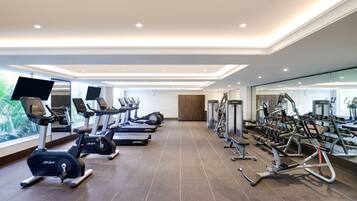 A modern gym with treadmills, elliptical machines, and weight equipment.
