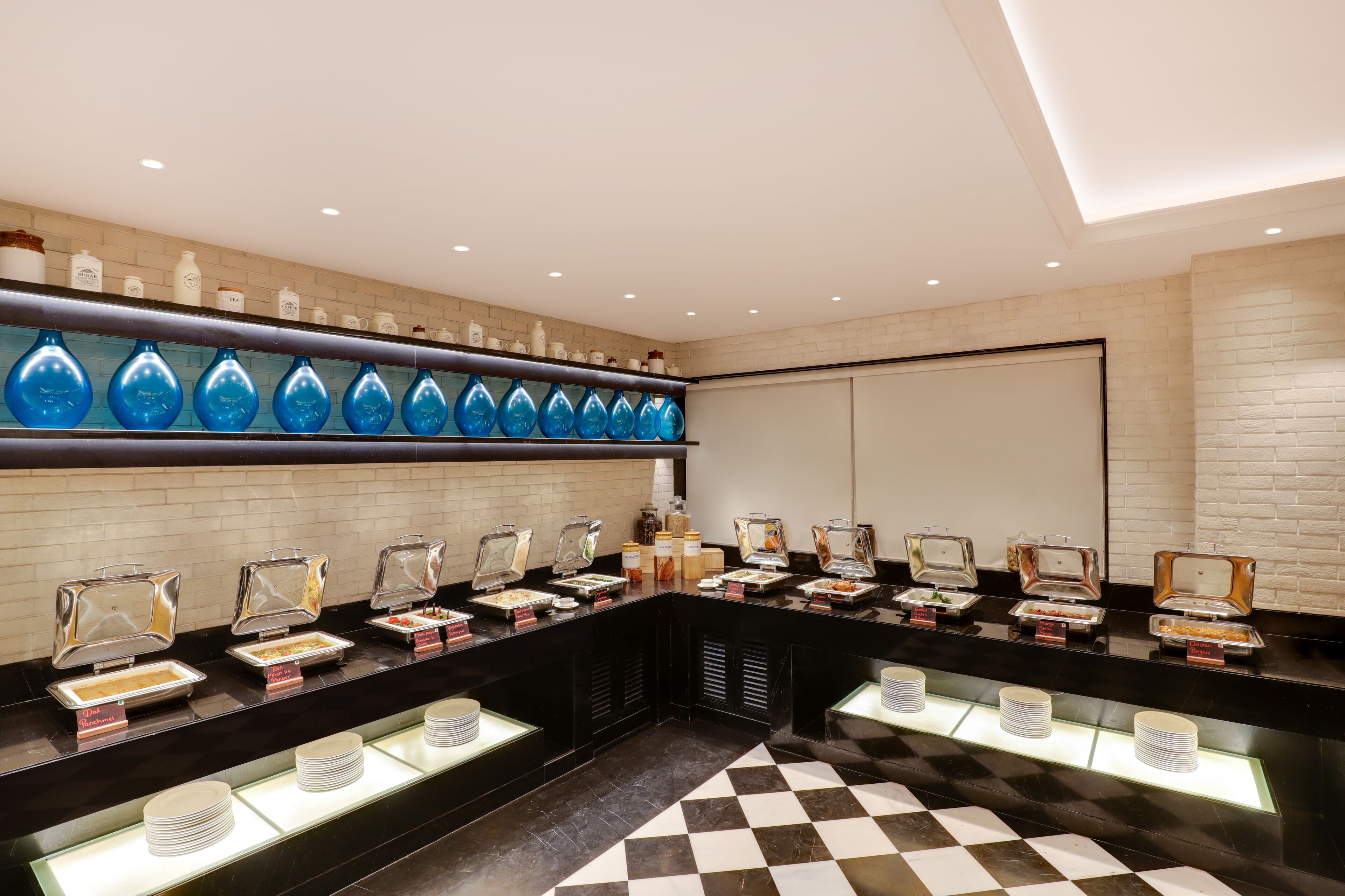 Een buffetgedeelte met diverse food stations, drinkglazen en een geruit vloertje.