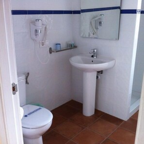 A small bathroom with a toilet, sink, and mirror. - Hostal Rural Sara (Villafeliche)